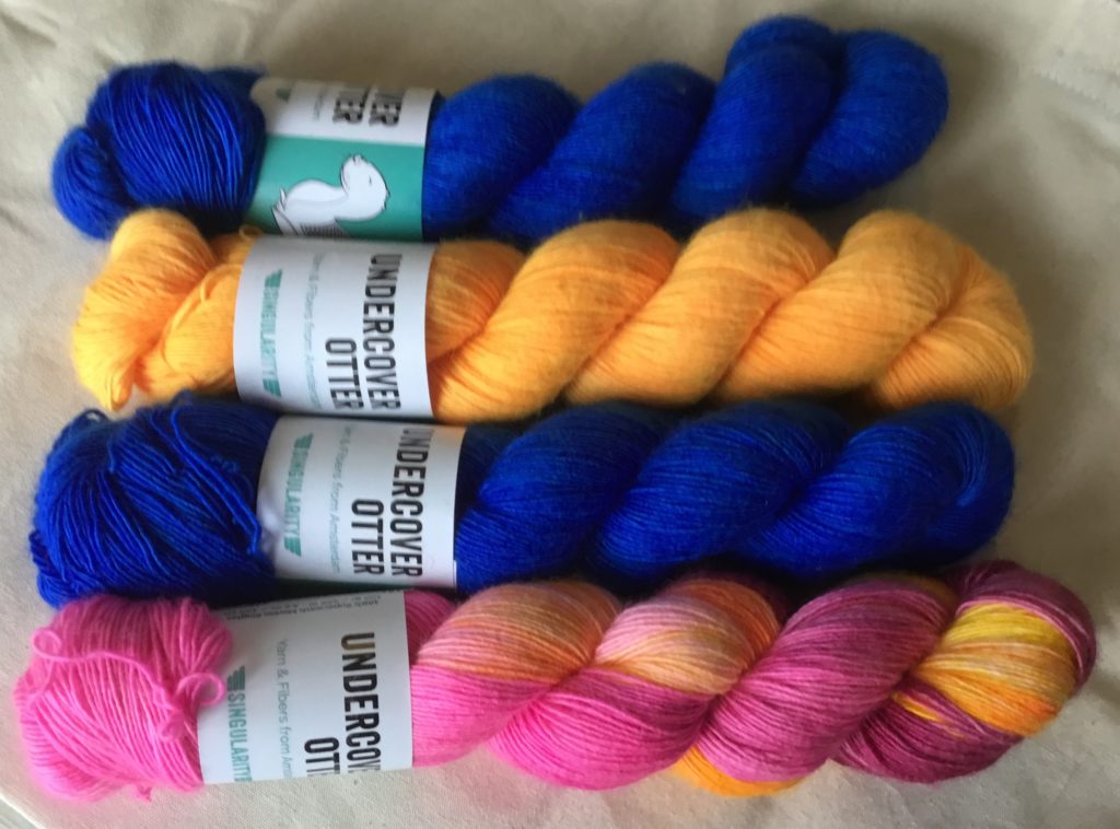 Alternating blue skeins with one orange and one orange and pink skein of Undercover Otter yarn