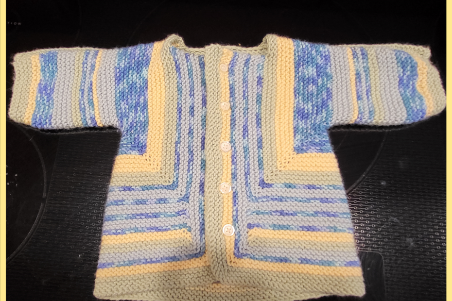 A striped baby jacket in blues, green, and yellow with little white buttons.