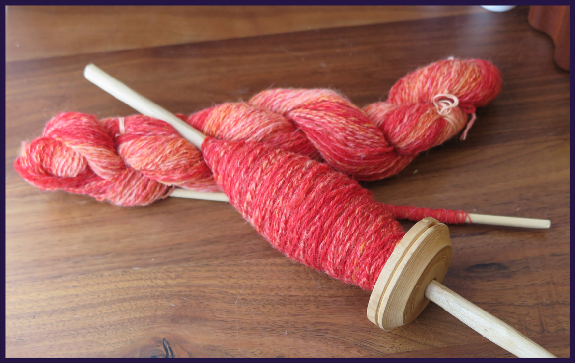 A skein of yarn and a cop on a spindle of the same pinkish orange tonal yarn spun in 3ply